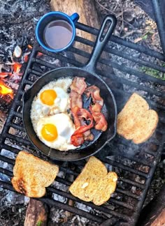 eggs, bacon and toast are cooking on an outdoor campfire with a cup of coffee