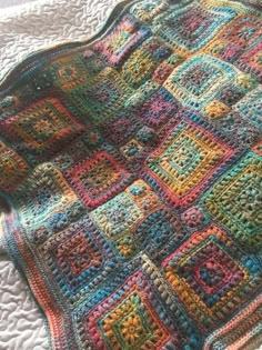 a multicolored crocheted blanket laying on top of a bed