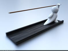 a white figurine holding a stick on top of a black tray