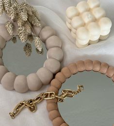 two mirrors and a chain on a white table cloth with flowers in the corner next to them