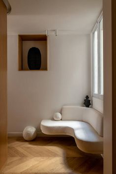 a white couch sitting next to a window on top of a hard wood floored floor