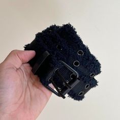 a hand holding a black belt with holes in it