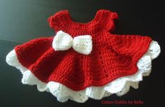 a crocheted red and white dress with a bow on the front, sitting on a black surface