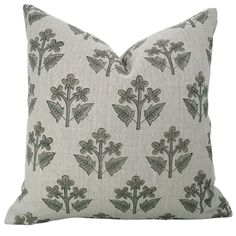 a white pillow with green leaves and flowers on the front, sitting on a white background