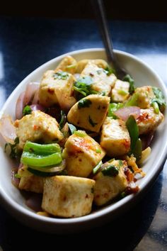 a white bowl filled with tofu and vegetables