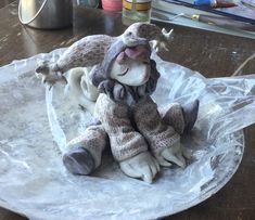 a small stuffed animal sitting on top of a plastic wrap around a tablecloth covered plate