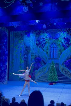 two ballerinas performing on stage in front of a christmas tree