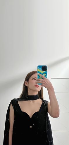 a woman taking a selfie in front of a mirror wearing a black dress and choker