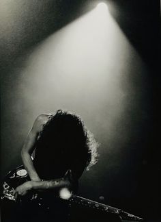 a woman playing guitar in front of a spotlight