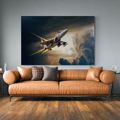 an airplane flying in the sky with clouds behind it on a wall above a couch