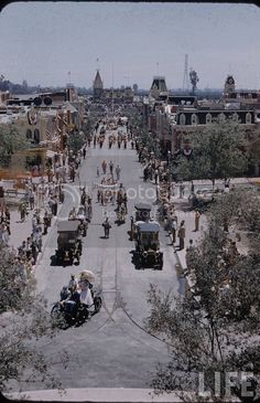 an aerial view of a street with many people on motorcycles and carriages in the middle