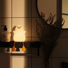 a duck lamp sitting on top of a shelf next to a vase