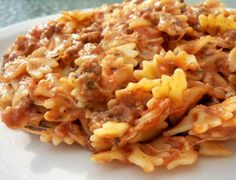 a white plate topped with pasta covered in meat and cheese on top of it's side