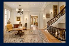 an ornate entry way with chandelier, rug and table in front of stairs