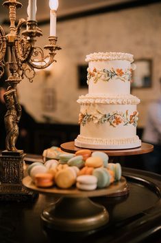 a three tiered cake sitting on top of a table next to a candelabra