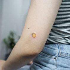 a person with a small orange tattoo on their left arm and the other half of her arm