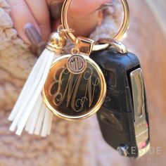 a person holding onto a car keychain with a monogrammed initials on it