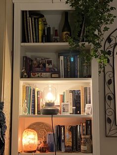 a bookshelf filled with lots of books next to a lamp