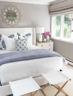 a white bed sitting in a bedroom next to two tables with chairs on top of it