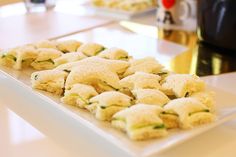 small appetizers are arranged on a long white plate at a restaurant countertop