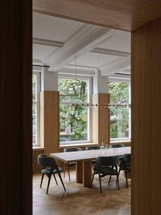 an empty room with several chairs and tables in front of two large windows that look out onto the woods