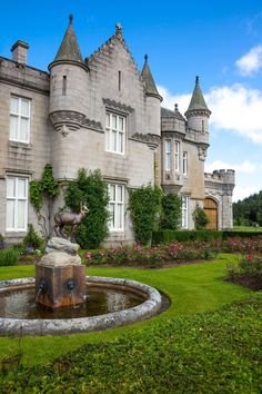 an old castle with a fountain in the front yard