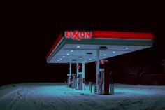 an exon gas station lit up at night in the snow with no people around