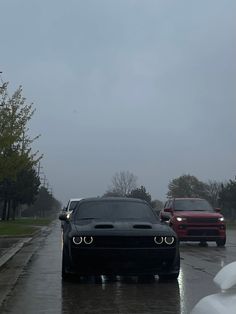 two cars driving down the road in the rain