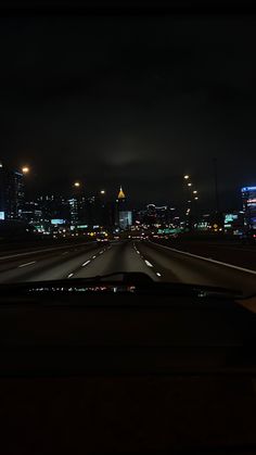 the city lights shine brightly in the distance as seen from inside a vehicle's dashboard