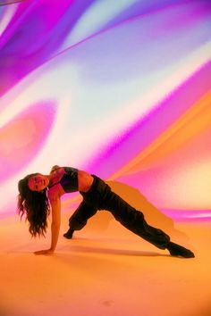 a woman is doing yoga in front of an abstract background