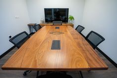 an empty conference table with black chairs and a flat screen tv