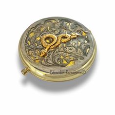 an ornate gold and silver box with a snake on the front, sitting on a white surface