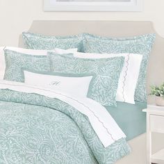 a bed with blue and white comforters and pillows on it's headboard