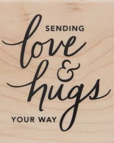 a wooden stamp with the words sending love and hugs your way written in black ink