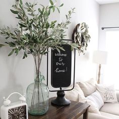 there is a vase with some green plants in it and a chalkboard on the wall