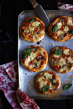 four small pizzas with cheese, mushrooms and basil