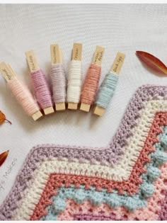 four crocheted wooden pins sitting on top of a white blanket next to autumn leaves