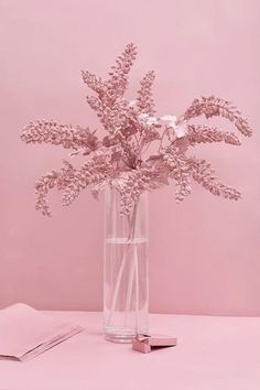 a vase filled with pink flowers on top of a table next to a notebook and pen