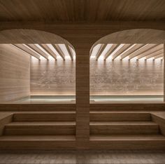 an empty sauna room with wooden walls and benches in the center, looking out to the water