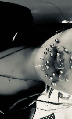 black and white photograph of a woman with spiked headpieces on her face sitting in a car