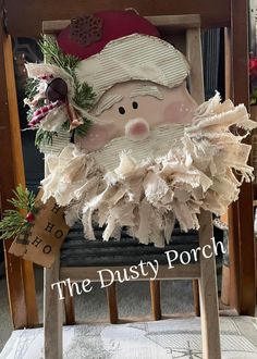 a wooden chair with a santa clause on it's back and the words, the dusty porch