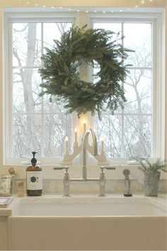 a white sink sitting under a window next to a wreath on top of a faucet