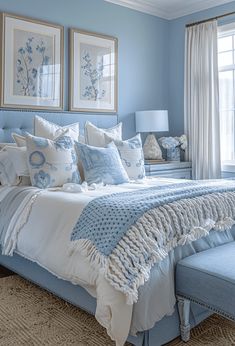 a bedroom with blue walls and white bedding in the center, along with two framed pictures on the wall