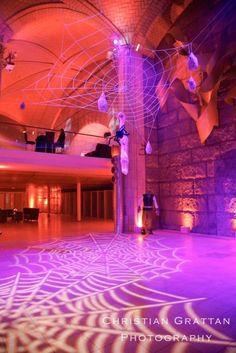 an indoor dance floor is lit up with purple lights and intricate designs on the ceiling