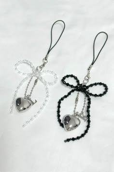 two black and white necklaces with bells attached to them on a white sheeted surface