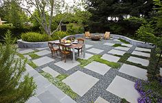 an outdoor dining area with chairs and table surrounded by greenery, shrubs and trees