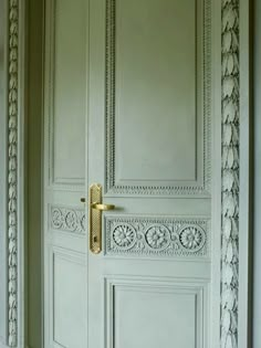 the door is painted white and has ornate carvings on it, along with a gold handle