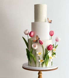 a three tiered cake decorated with flowers and butterflies