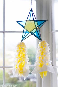 a star hanging from the side of a window next to two white and yellow flowers