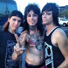 three young men posing for the camera with their fingers in the air and tattoos on their arms